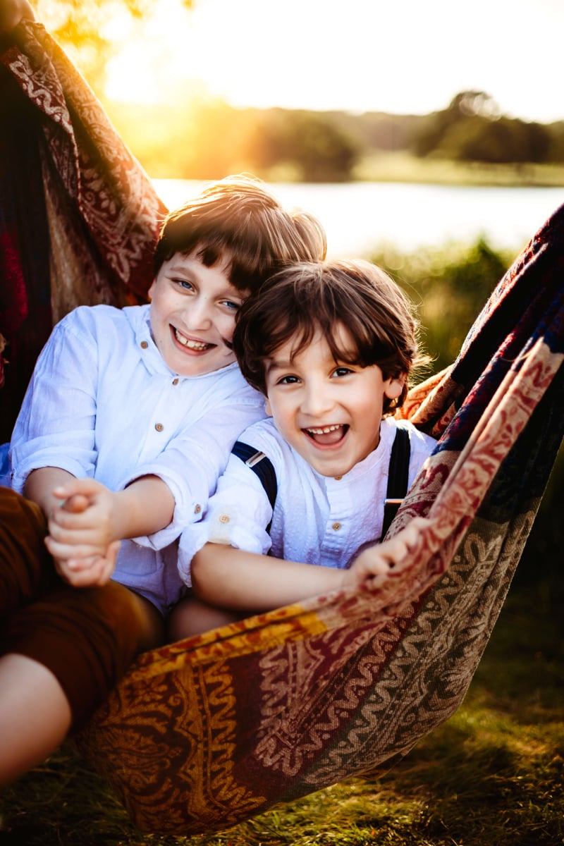 London Family Photographer, two brothers share a hammock outdoors, both giggling