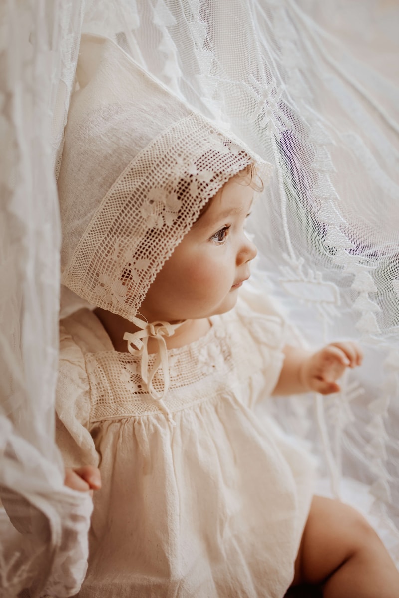 London Family Photographer, a happy baby girl lays in white linens