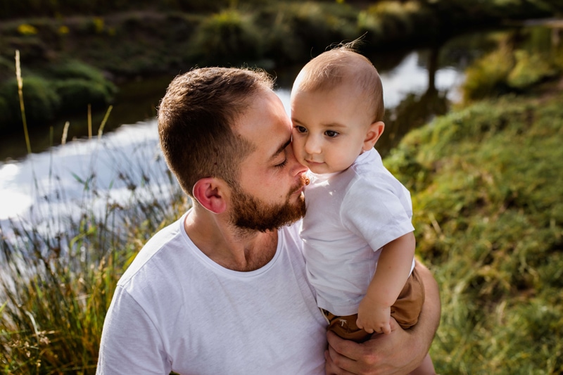 London Family Photographer, a young father cuddles into his baby son outdoors